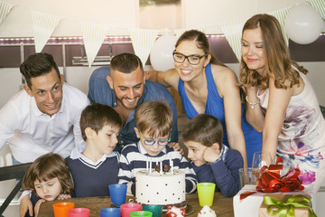  happy families with children celebrating around a cake for a bir