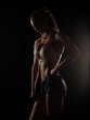 © maksimvostrikov - Beautiful athletic young woman with slim muscular body (perfect abdominal muscles, strong biceps, sexy buttocks) wearing the sportswear is posing on the dark black studio background, diet and fitness