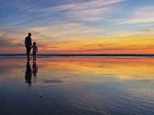 Silhouette Of Father And Child At Beach Shoreline During Sunset