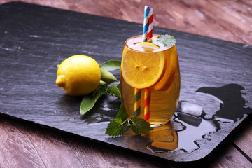 Iced tea with lemon slices, mint and ice on rustic background