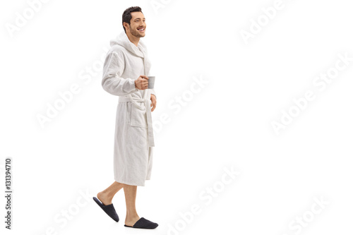 Fotografie, Obraz Young man in a bathrobe holding a cup and walking