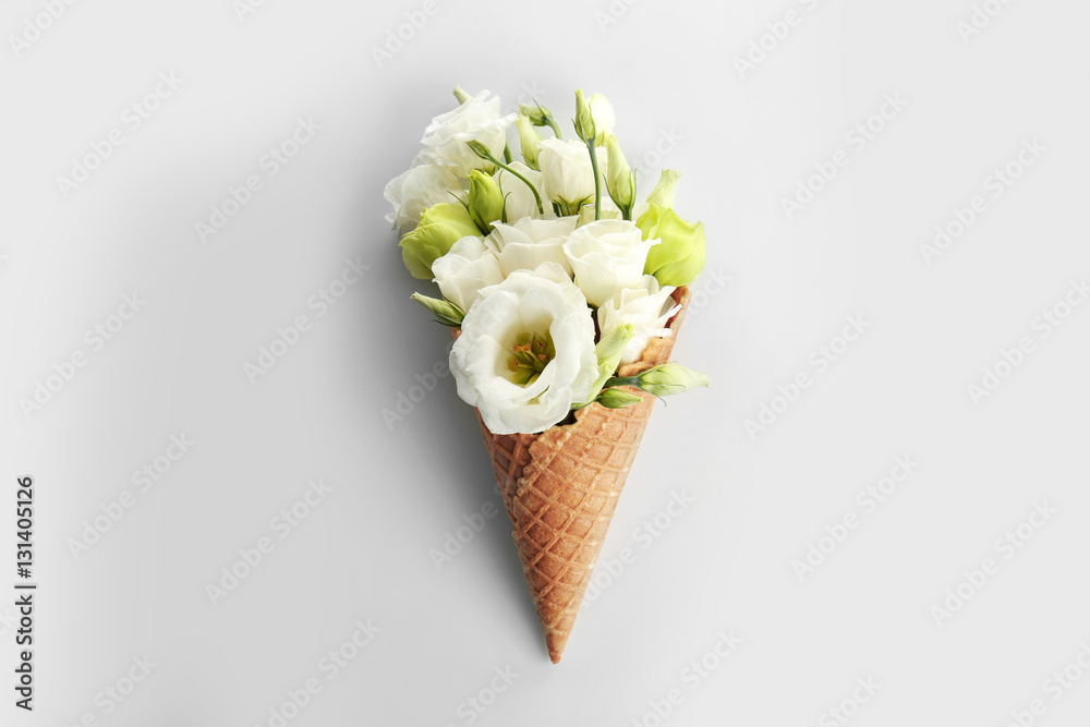 Waffle cone with bouquet of beautiful flowers on white background