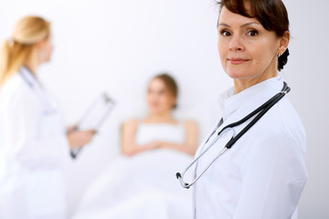 Wall Mural - Female doctor smiling on the background with patient and his doctor