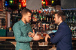 © newagecinema - two young man talking at counter.  friends standing in bar and drinking whisky