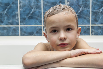 Adorable baby boy with shampoo soap suds on hair taking bath. Cl