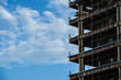 high-rise building under construction showing steel frame work against a blue sky with white clods