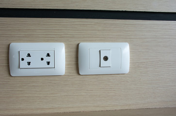 Close up picture of White Cable TV outlet receptacle and plug socket on the  brown wall.