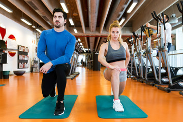 Wall Mural - Sporty young couple doing muscular exercise in gym.