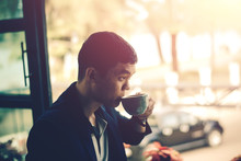 Young Businessman Looking To Relax From Work By Sipping Coffee.