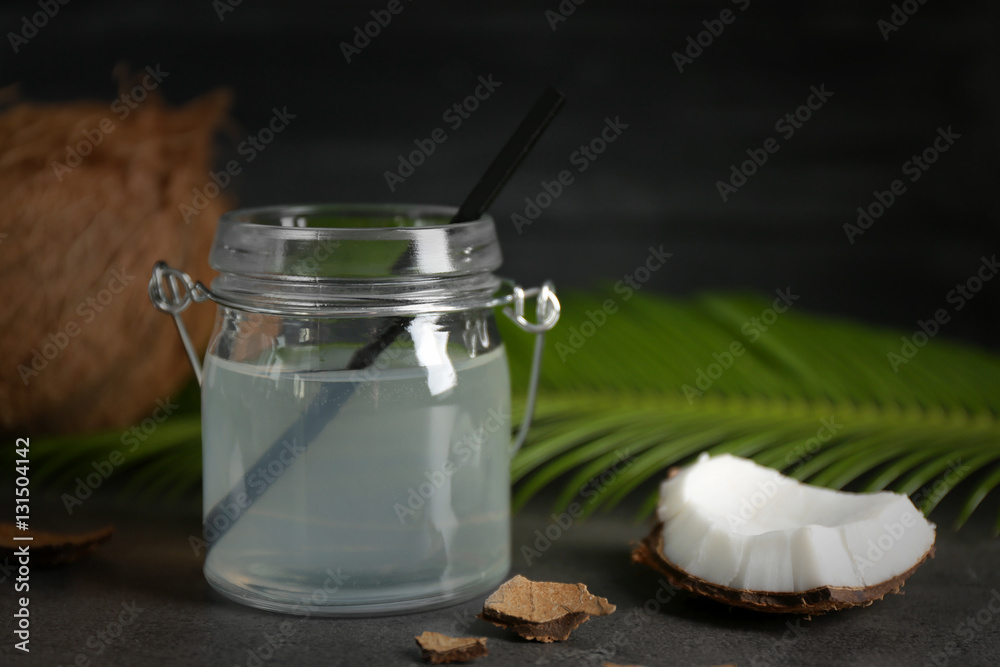 Mason jar with coconut water and fresh nuts on dark background