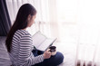 © nipastock - female hands holding coffeecup in front of opened book