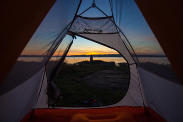 women sit front of camping tent glow up with sunrise in morning