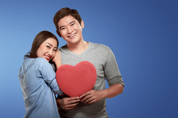 Happy asian couple leaning and holding heart shape