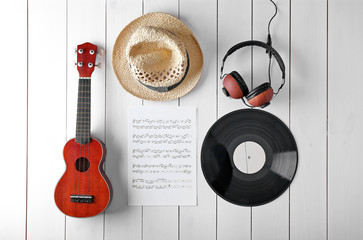 Wall Mural - Small guitar, headphones, music sheets and straw hat on wooden surface, top view