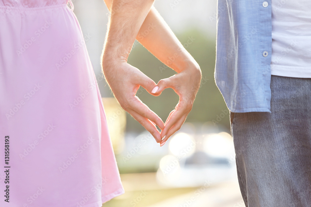 Young couple holding hands in shape of heart