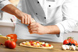 © Africa Studio - Male hands preparing pizza at wooden table closeup