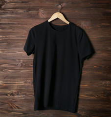 Wall Mural - Blank black t-shirt against wooden background