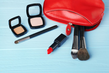 Wall Mural - Red make up bag and decorative cosmetics on turquoise wooden background