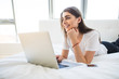 © F8  \ Suport Ukraine - Portrait of beautiful happy young woman lying in bed and using laptop at home