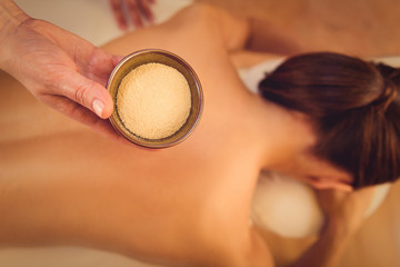 Girl getting back massage by clay powder