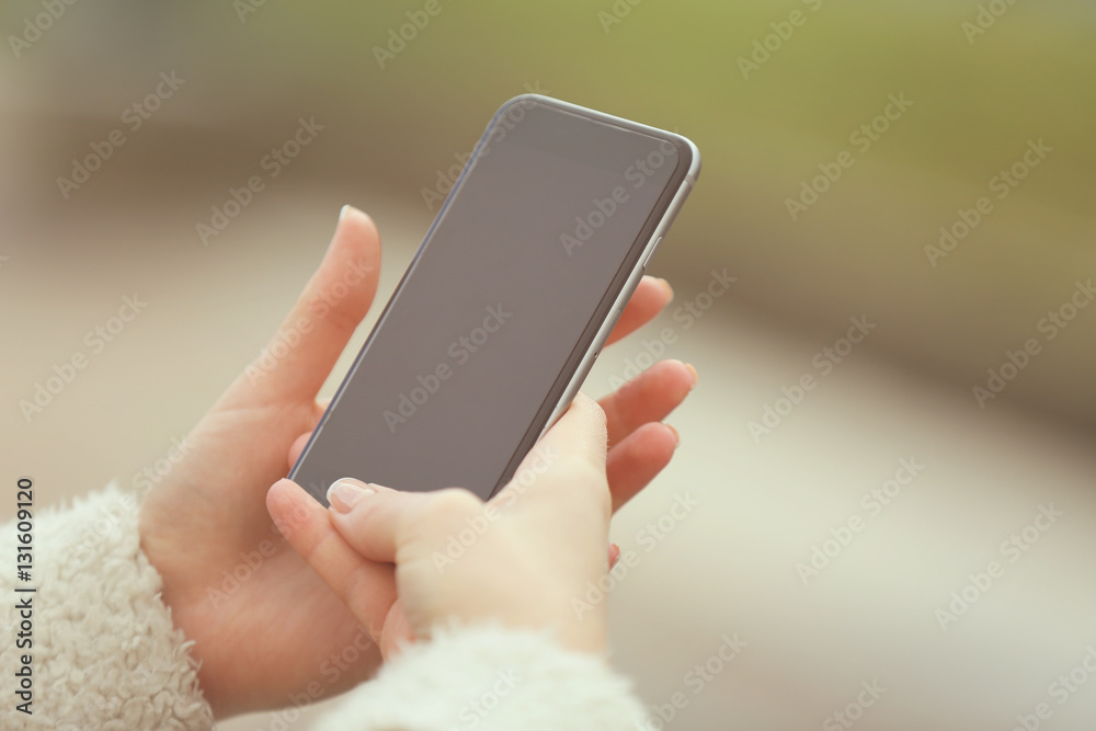 Woman holding smart phone, outdoors