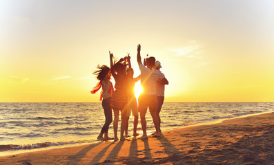 Wall Mural - group of happy young people dancing at the beach on beautiful summer sunset