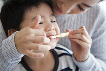 Mother is brushing her son's teeth