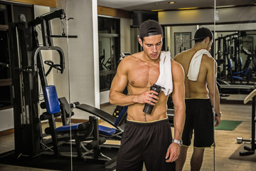 Wall Mural - Muscular young man resting in gym during workout