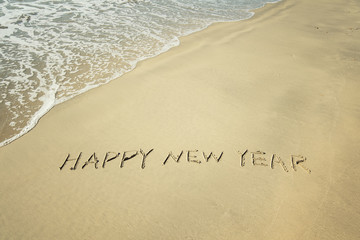 Wall Mural - happy new year written in sand write on tropical beach