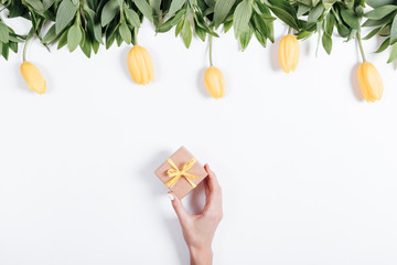 Female hand puts a small box with a gift on the table with yello