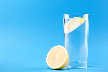 Wall Mural - glass of water with lemon on a blue background