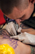 © pavel_shishkin - Tattoo artist making picture on female body