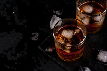 Alcohol whiskey cocktail with cola and ice. On the black table.