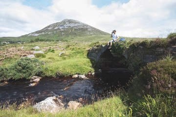 Lone walker stood on an old bridge in the poisoned Glen with a v