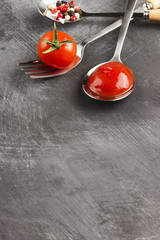 Tomato sauce, cherry, spices in fork and spoons on a dark backgr