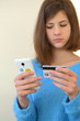Молодая девушка в голубом свитере с банковской картой и сенсорным телефоном в руках, банковские платежи 