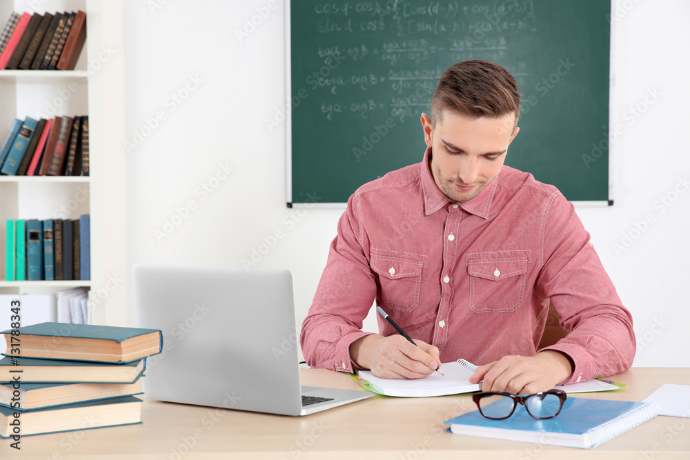 Young male teacher working in classroom