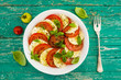 Delicious caprese salad with ripe tomatoes and mozzarella cheese with fresh basil leaves. Italian food. 