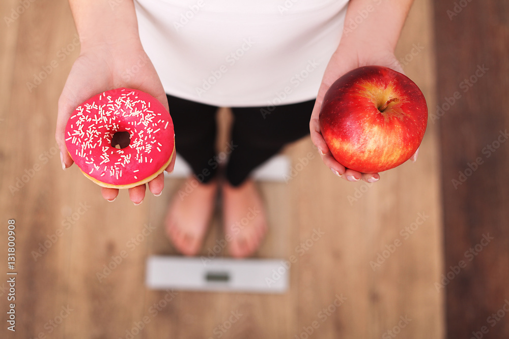 Diet. Woman Measuring Body Weight On Weighing Scale Holding Donut and apple. Sweets Are Unhealthy Junk Food. Dieting, Healthy Eating, Lifestyle. Weight Loss. Obesity. Top View - obrazy, fototapety, plakaty 