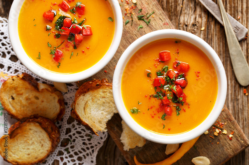Fotografie, Obraz Homemade pumpkin soup in a white ceramic bowl on a wooden rustic table, nutritio