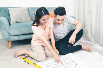 Wall Mural - Attractive young asian adult couple looking at house plans.