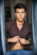 © theartofphoto - Portrait of sexy young man, buttoning shirt, looking out of window during the day