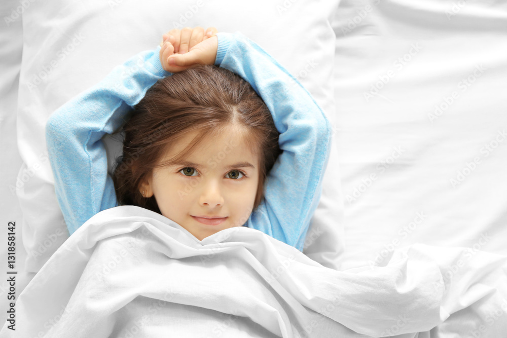Funny little girl lying in bed at home