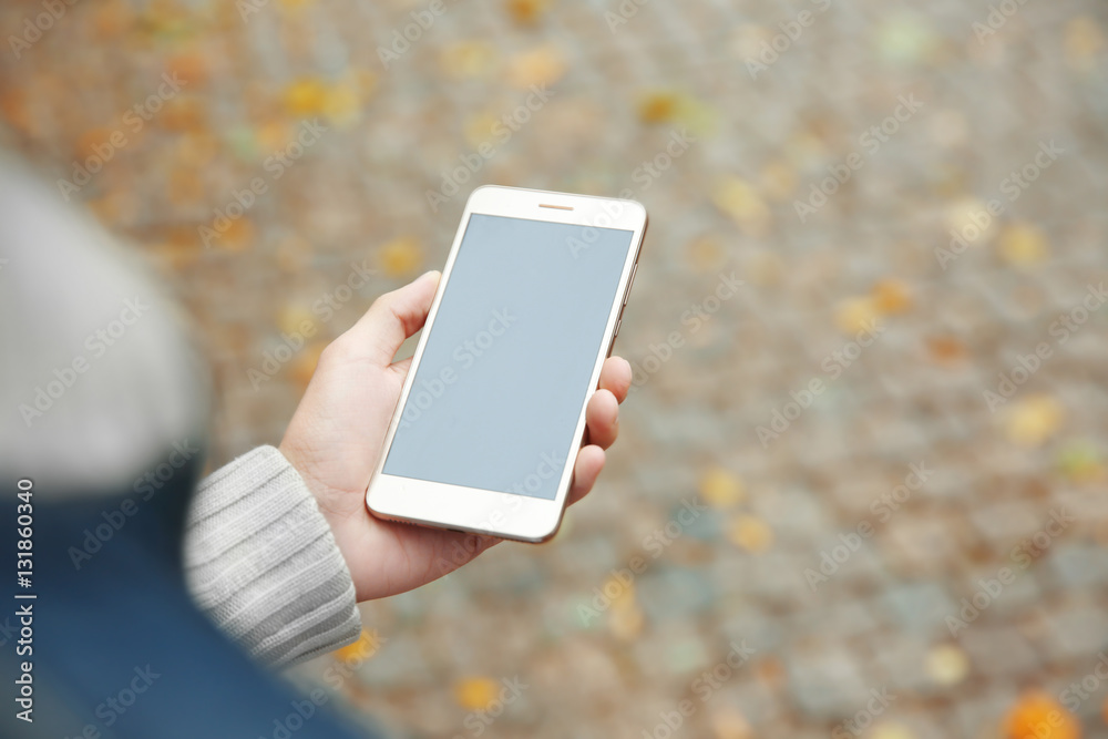 Man holding smart phone on blurred paving stone background