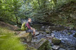 © Westend61 - Hiker in forest sitting on rocks at a brook