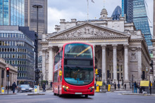 London, England - Iconic Red Double Decker Bus On The Move And The Royal Exchange Building At Background