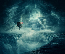 StormFall Inspirational Imaginary View, Scary Landscape As A Hot Air Balloon Fly Over The Chasm Of A Foggy Waterfall Below A Dark Stormy Sky.