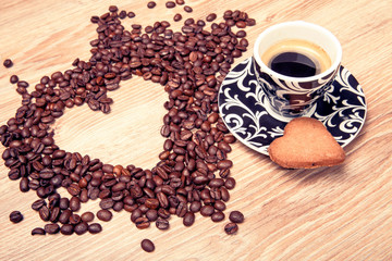 Heart make whit coffee beans and cup whit espresso and sweet heart cookie on wood table background. 