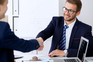 Business handshake at meeting or negotiation in the office. Partners are satisfied because signing contract or financial papers