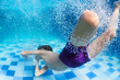 © Tropical studio - Funny portrait of boy swimming and diving in blue pool with fun - jumping deep down underwater with splashes and foam. Family lifestyle and summer children water sports activity with parents.